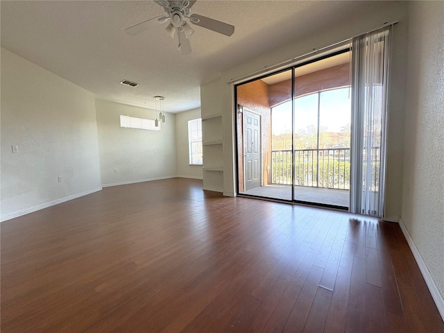 empty room with ceiling fan, dark hardwood / wood-style floors, and a textured ceiling