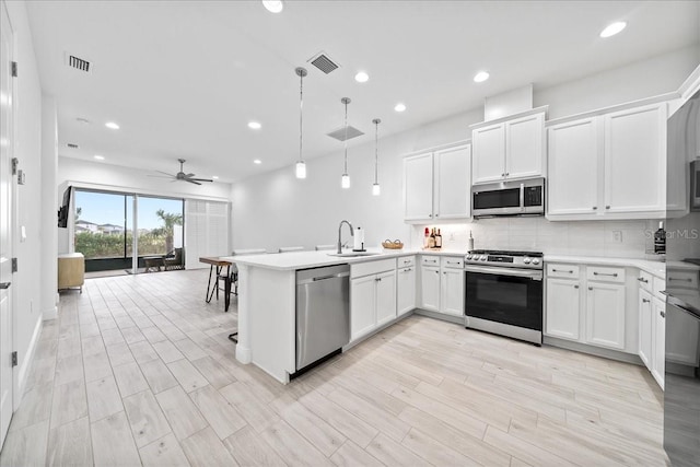 kitchen with sink, white cabinetry, hanging light fixtures, kitchen peninsula, and stainless steel appliances