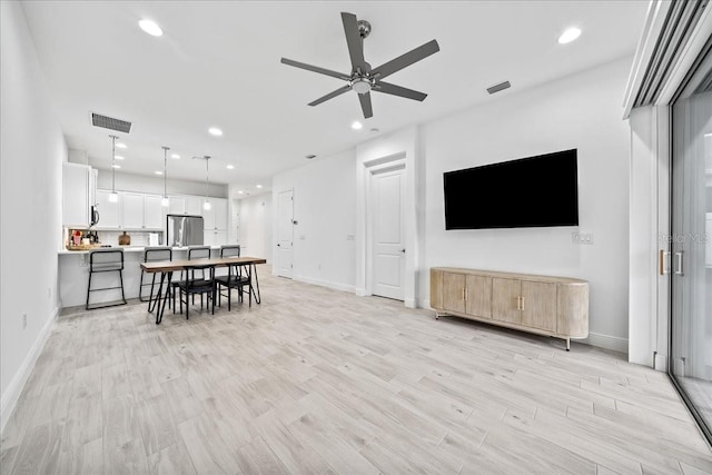 living room with light hardwood / wood-style flooring and ceiling fan