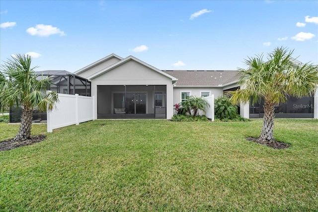 rear view of property with a lawn, a sunroom, and glass enclosure