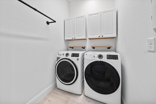 washroom with light hardwood / wood-style flooring, cabinets, and washing machine and clothes dryer