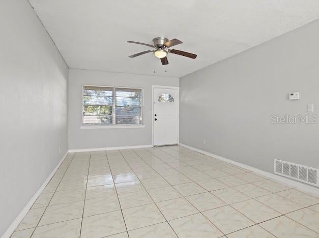 empty room with ceiling fan and light tile patterned floors