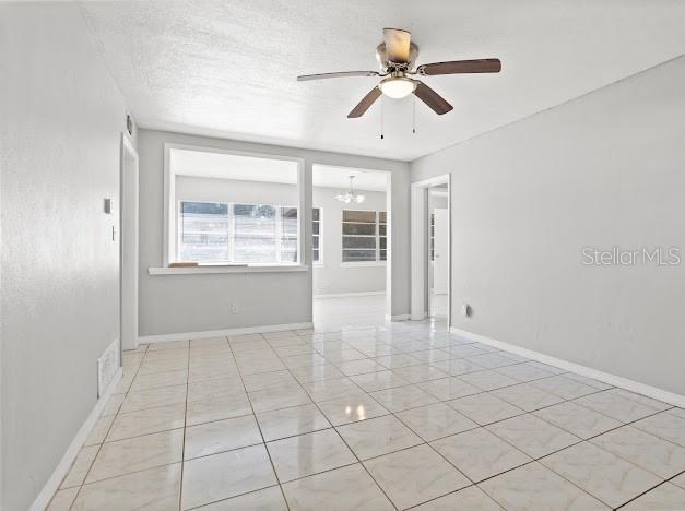 unfurnished room featuring ceiling fan with notable chandelier and a textured ceiling