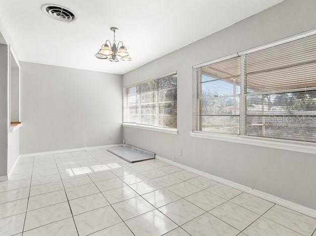 unfurnished dining area featuring light tile patterned flooring and a chandelier