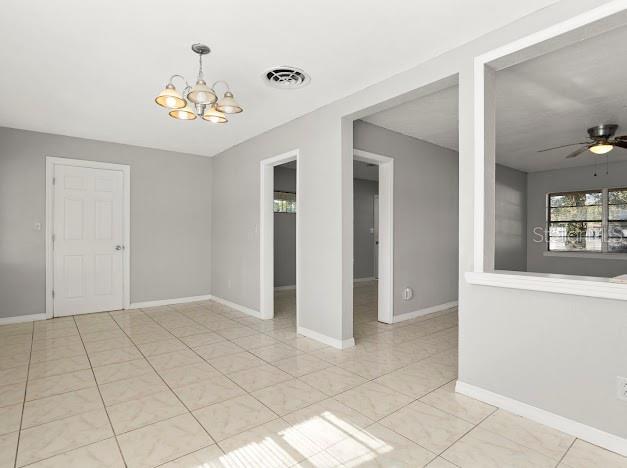 empty room featuring ceiling fan with notable chandelier