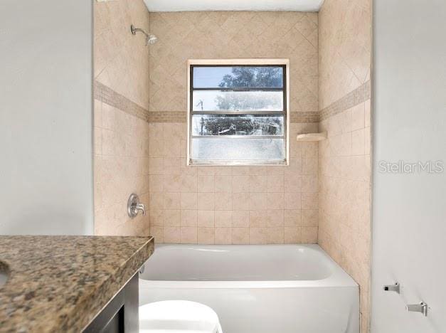 full bathroom featuring toilet, vanity, and tiled shower / bath