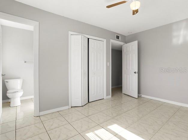 unfurnished bedroom featuring a closet, ceiling fan, and connected bathroom