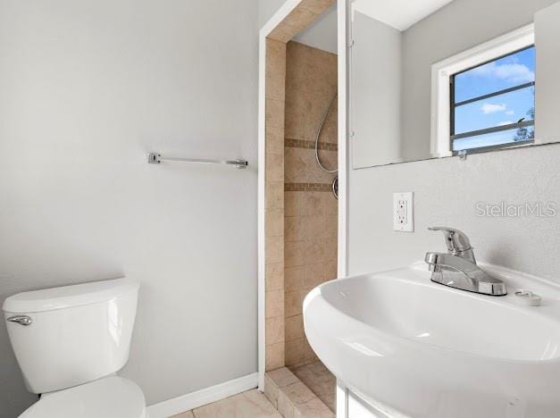 bathroom featuring sink, tile patterned floors, toilet, and a tile shower