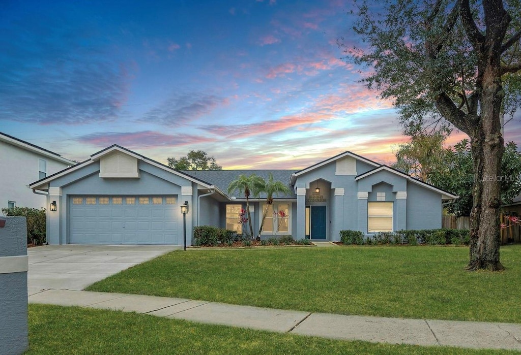 ranch-style home featuring a garage and a yard