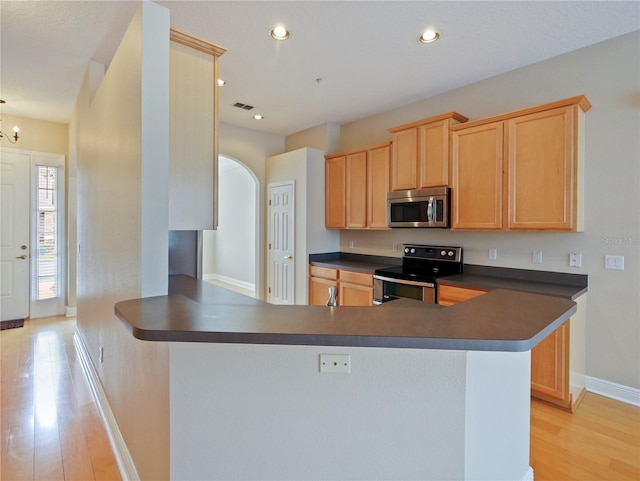 kitchen with light hardwood / wood-style floors, kitchen peninsula, light brown cabinets, and stainless steel appliances