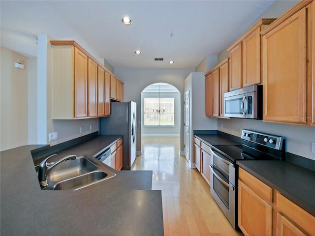 kitchen with light wood-type flooring, an inviting chandelier, appliances with stainless steel finishes, and sink