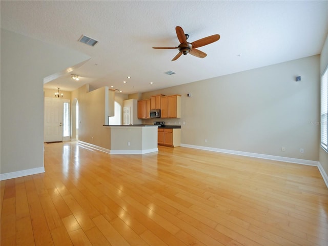 unfurnished living room featuring a textured ceiling, ceiling fan with notable chandelier, and light hardwood / wood-style flooring