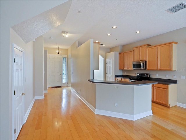 kitchen with light wood-type flooring, a chandelier, a textured ceiling, and range with electric cooktop