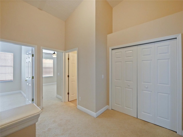 interior space featuring high vaulted ceiling, light colored carpet, and a closet