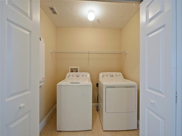 clothes washing area featuring light tile patterned floors, independent washer and dryer, and a textured ceiling