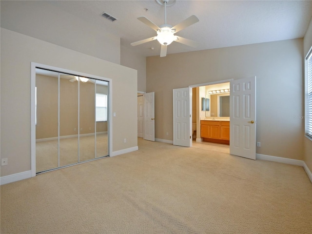 unfurnished bedroom with vaulted ceiling, ceiling fan, a closet, and light colored carpet