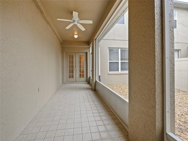 unfurnished sunroom featuring ceiling fan and french doors