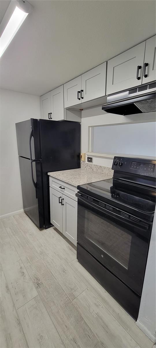 kitchen featuring white cabinetry, black appliances, and light hardwood / wood-style flooring