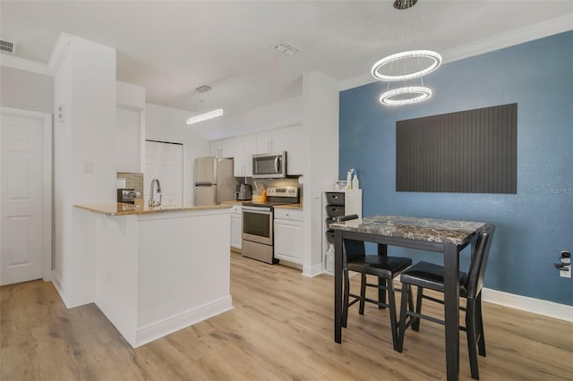 kitchen with tasteful backsplash, light hardwood / wood-style flooring, appliances with stainless steel finishes, kitchen peninsula, and white cabinets