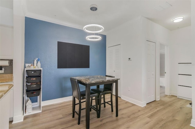 dining space featuring ornamental molding and light hardwood / wood-style floors