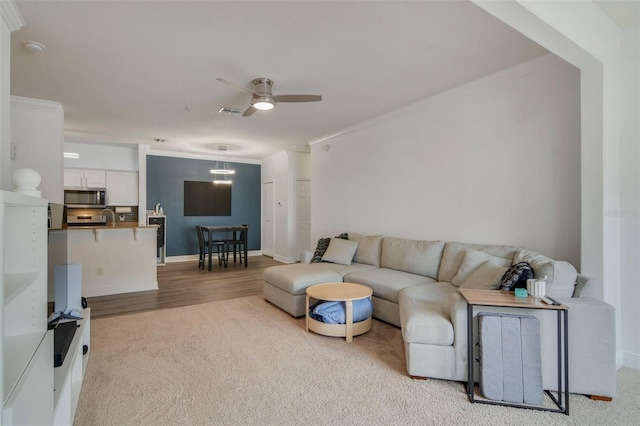 carpeted living room featuring crown molding and ceiling fan with notable chandelier