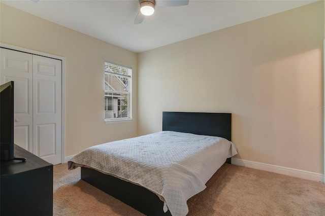 bedroom with ceiling fan, light carpet, and a closet