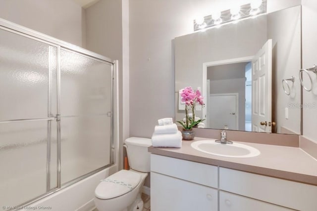 full bathroom featuring vanity, bath / shower combo with glass door, and toilet