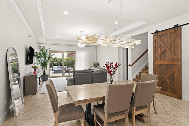 dining area with a barn door, ornamental molding, and a raised ceiling