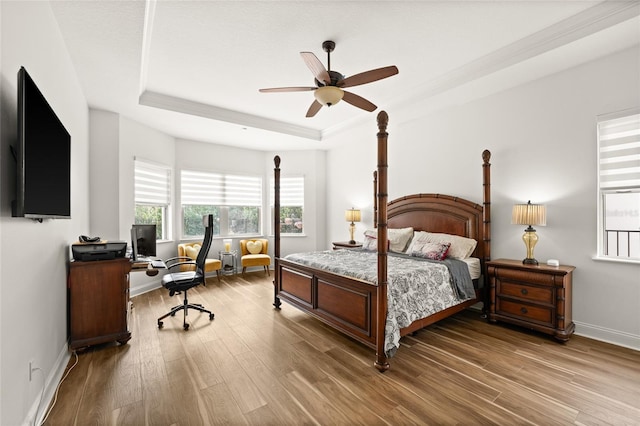 bedroom with baseboards, a tray ceiling, ceiling fan, and wood finished floors