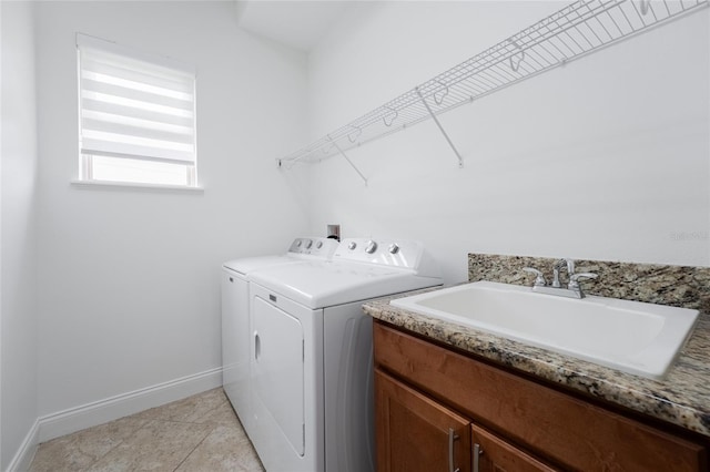 laundry room featuring light tile patterned floors, cabinet space, baseboards, washing machine and dryer, and a sink