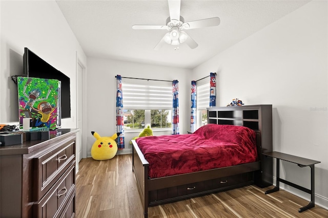 bedroom with ceiling fan, baseboards, and wood finished floors