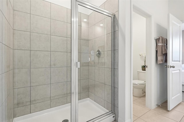 bathroom featuring toilet, tile patterned floors, and a shower with shower door