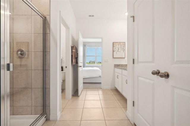 bathroom featuring tile patterned flooring, a shower with shower door, vanity, and toilet