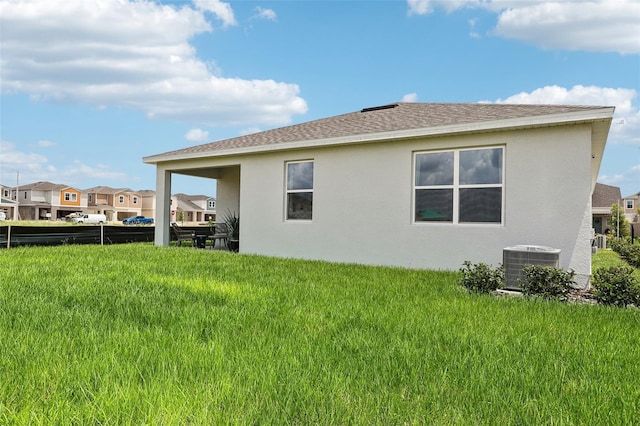 back of house featuring central air condition unit and a lawn