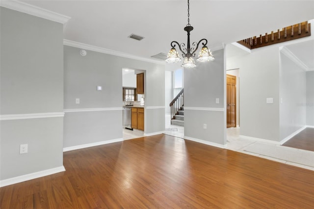 empty room featuring crown molding, a chandelier, and light hardwood / wood-style flooring