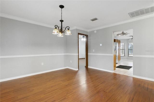 unfurnished room featuring hardwood / wood-style floors, ornamental molding, and a chandelier