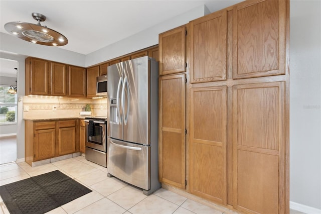 kitchen featuring light tile patterned floors, decorative backsplash, and stainless steel appliances