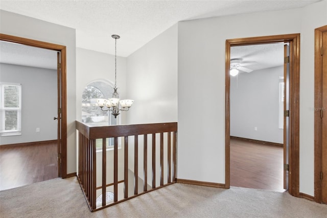 corridor featuring light carpet, a notable chandelier, and a healthy amount of sunlight