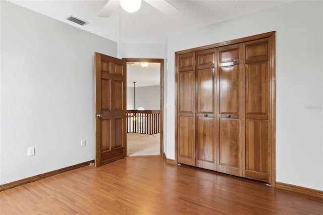 unfurnished bedroom with hardwood / wood-style floors, a textured ceiling, a closet, and ceiling fan