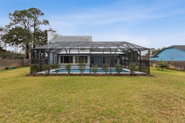 rear view of house with a fenced in pool, a lanai, and a yard