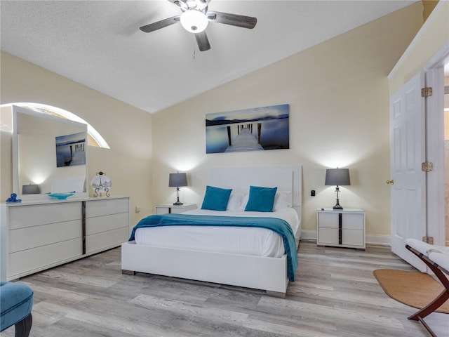 bedroom with vaulted ceiling, light wood-type flooring, ceiling fan, and a textured ceiling