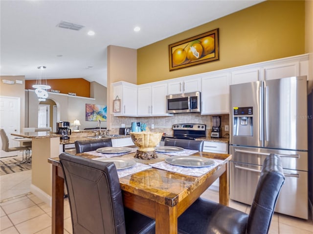 kitchen featuring light stone countertops, hanging light fixtures, stainless steel appliances, light tile patterned floors, and white cabinetry