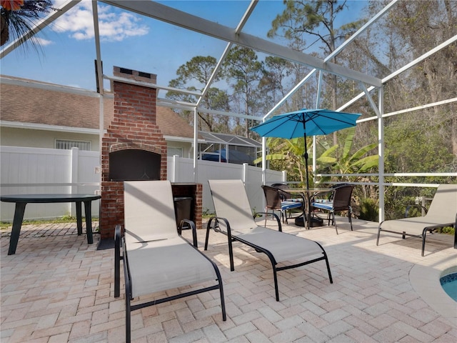 view of patio featuring a lanai and a brick fireplace