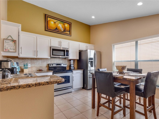 kitchen featuring stainless steel appliances, light tile patterned floors, white cabinets, and sink