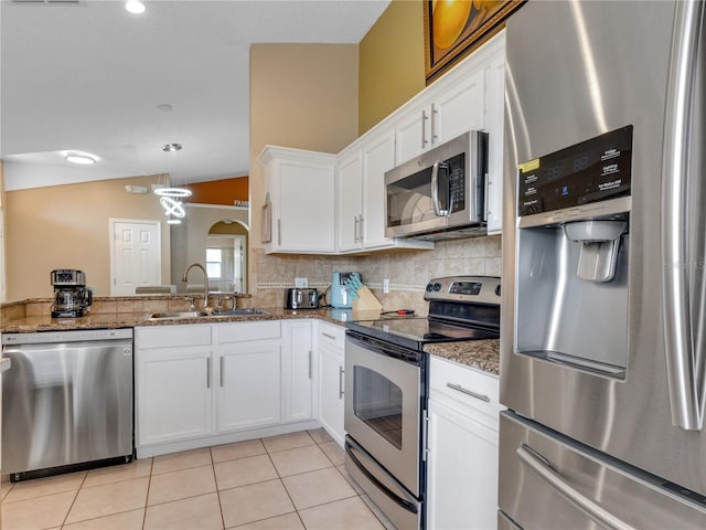 kitchen with stainless steel appliances, white cabinetry, sink, and dark stone counters