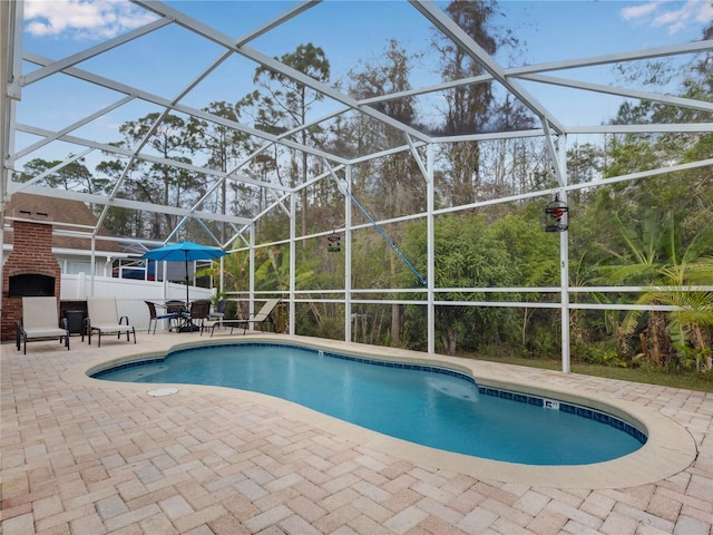 view of pool featuring a brick fireplace, a lanai, and a patio