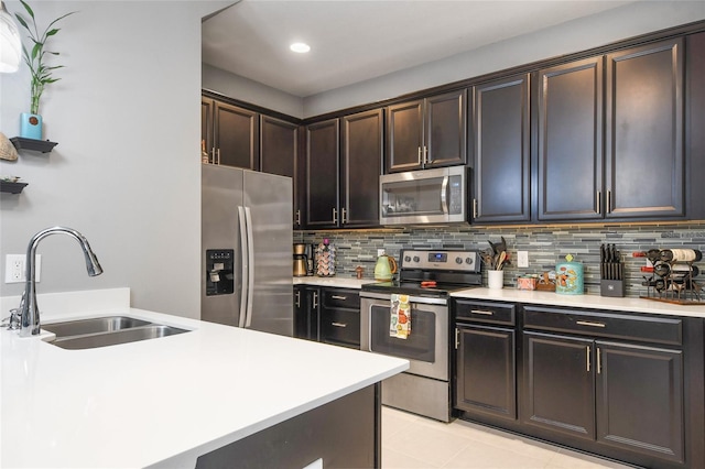 kitchen featuring light tile patterned floors, tasteful backsplash, appliances with stainless steel finishes, dark brown cabinets, and sink