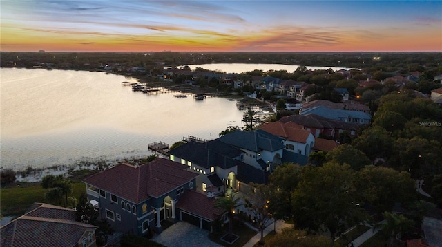 aerial view at dusk featuring a water view