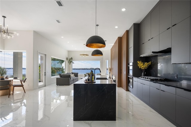 kitchen with hanging light fixtures, tasteful backsplash, a water view, and a chandelier