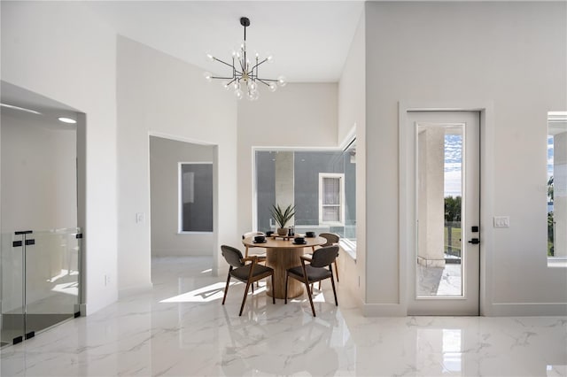 dining area with a towering ceiling and a notable chandelier